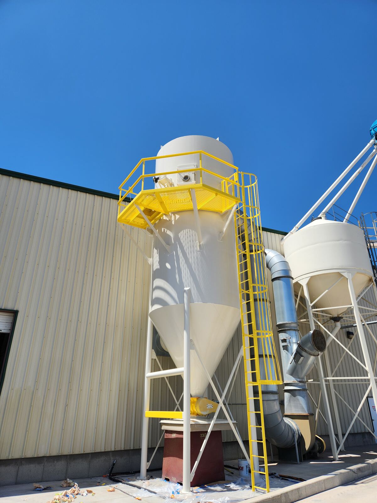 The recoated dust collector tank in white with safety-yellow ladder and platform