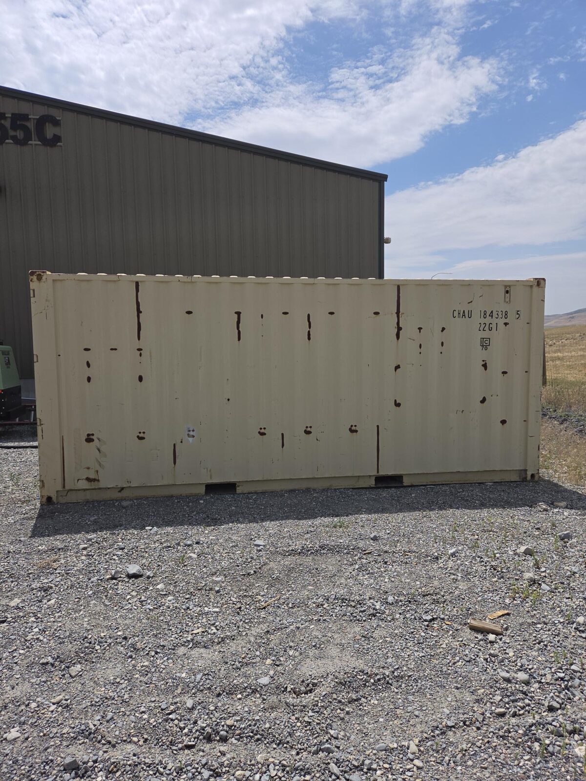 Jobsite storage shipping container with faded, chalked paint and rust streaks before sandblasting
